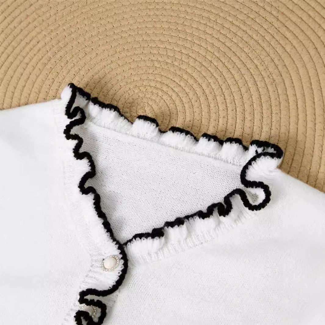 Pull à manches longues et col en V avec boutons en nacre et boucles d'oreilles en bois contrastées.