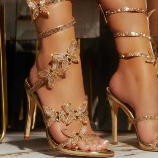 Sandales à talons aiguilles papillon ornées de strass en noir, rose et or
