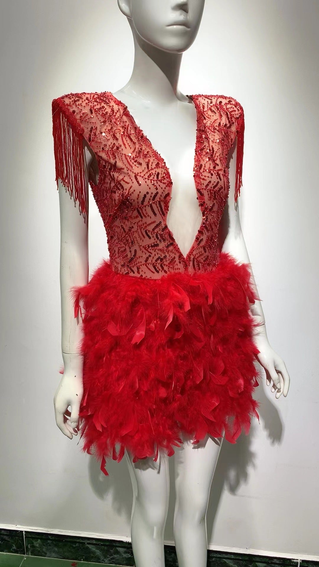 Robe courte sans manches rouge, décolleté en V profond, avec jupe à franges et plumes